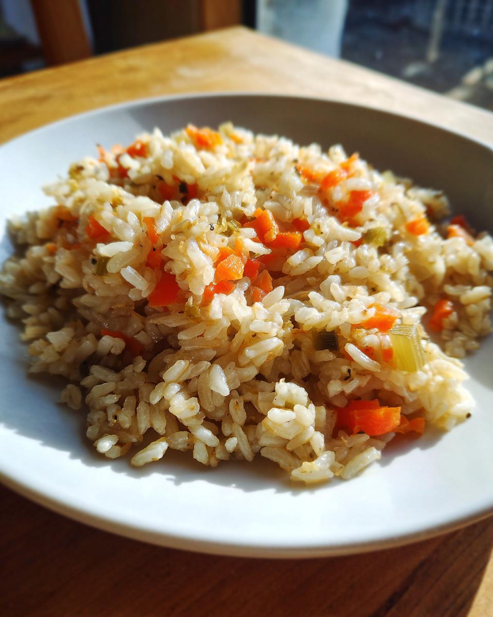 A close-up of a serving of flavorful brown rice recipes mixed with diced carrots and celery.