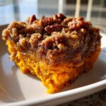 Close-up of a serving of Ruths Chris Sweet Potato Casserole with a crunchy pecan topping.