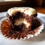 Close-up of a Swirled Chocolate Cupcakes with a bite taken out, showing the marbled chocolate and vanilla interior.