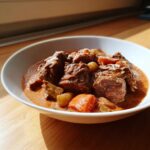 A close-up of tender chunks of beef and vegetables in a rich, reddish-brown sauce, representing the Tuscan Beef Casserole.