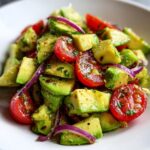 Close-up of a colorful salad featuring cubed avocado, sliced cherry tomatoes, and red onion, perfect for Keto Avocado Recipes.