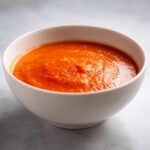 Close-up of bright orange, creamy soup in a white bowl, perfect for Immersion Blender Recipes.