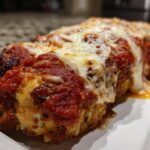 Close-up of a piece of golden brown Baked Chicken Parmesan topped with rich marinara sauce and melted mozzarella cheese.