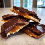 A stack of homemade Caramel Ritz Cracker Christmas Cookies showing the crispy cracker, gooey caramel, and chocolate topping.