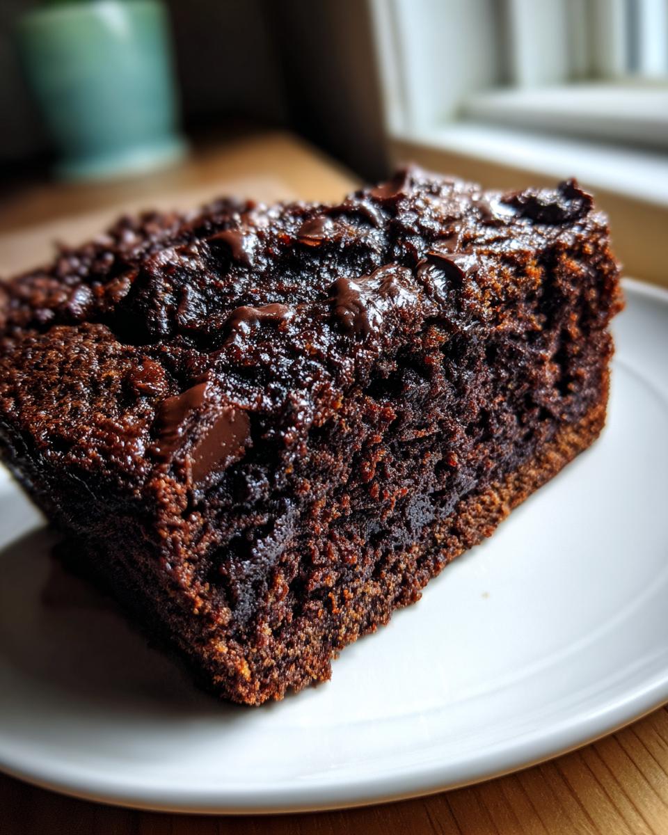 Close-up of a rich, dark slice of Double Chocolate Zucchini Bread with melted chocolate chips on top.