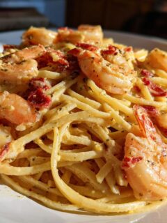 A close-up shot of creamy Marry Me Shrimp Pasta featuring large seasoned shrimp and sun-dried tomatoes tossed with spaghetti.