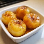 Four perfectly cooked Microwave Baked Apples, glistening with cinnamon sugar glaze, served in a small white baking dish.