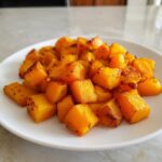 A white plate filled with perfectly roasted, caramelized cubes of butternut squash, a great example of butternut squash recipes.