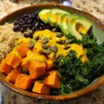 A vibrant Anti Inflammatory Glow Bowl featuring quinoa, black beans, roasted sweet potatoes, kale, avocado, and a yellow turmeric dressing.