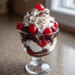 Close-up of a layered Black Forest Trifle featuring chocolate cake, whipped cream, cherries, and chocolate shavings.