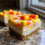 A close-up of a square slice of rich Candy Corn Cheesecake Bars with a graham cracker crust.