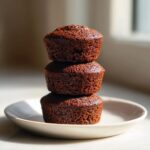 Three rich, dark Chocolate Gingerbread Mini Cakes stacked vertically on a small white plate.