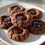 A stack of rich, dark Chocolate Thumbprint Cookies rolled in sugar and filled with glossy melted chocolate.