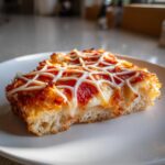 Close-up of a slice of Creepy Spider Web Pizza showing thick crust, pepperoni, and white cheese webbing.