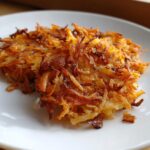 Close-up of two perfectly crispy, golden brown Haunted Hash Browns served on a white plate.