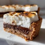A close-up cross-section of a Mini Smores Pie showing a graham cracker crust, melted chocolate, and toasted marshmallow topping.