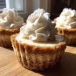 A close-up of a single No Bake Gingerbread Cheesecake Cup topped with a swirl of whipped cream, sitting on a wooden surface.