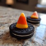 A close-up of an Oreo Witch Hat Cookie topped with a candy corn piece.