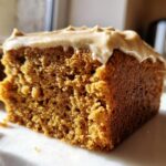 Close-up of a moist slice of Pumpkin Spice Latte Cake topped with light brown frosting.