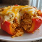 Close-up of a baked red bell pepper stuffed with cheesy Shredded Chicken Rice Stuffed filling.