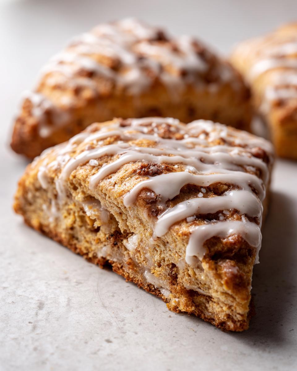 Close-up of a freshly baked Starbucks Pumpkin Scones slice drizzled with white icing.