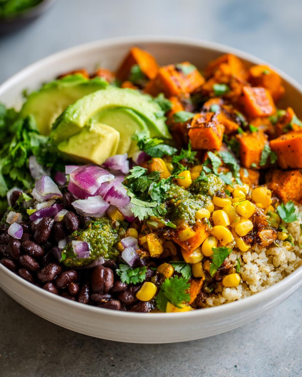 A close-up of a healthy Sweet Potato Taco Bowl featuring roasted sweet potatoes, black beans, corn, avocado, and green sauce.