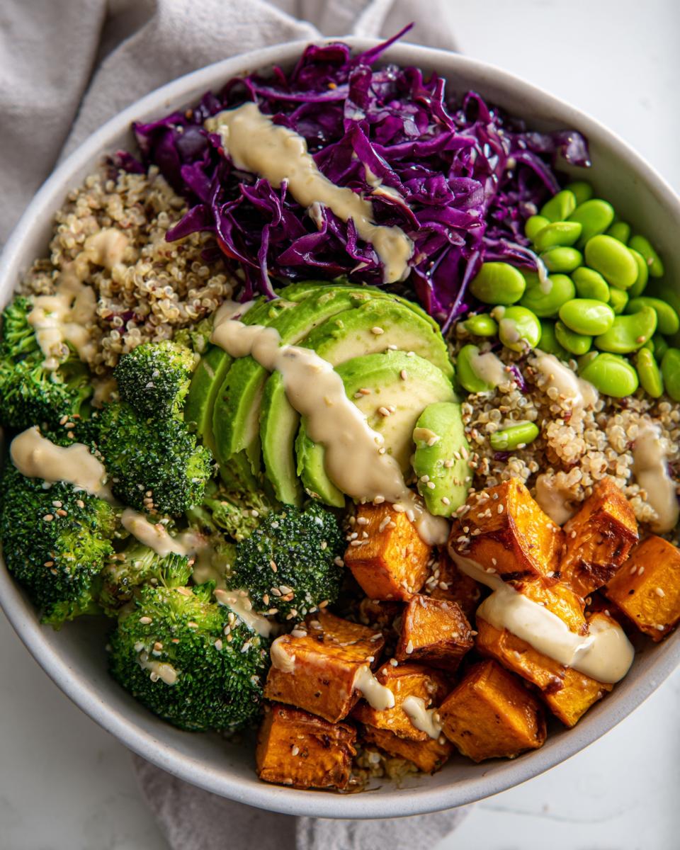 Close-up of a vibrant Vegan Buddha Bowl featuring roasted sweet potatoes, avocado, broccoli, and red cabbage.