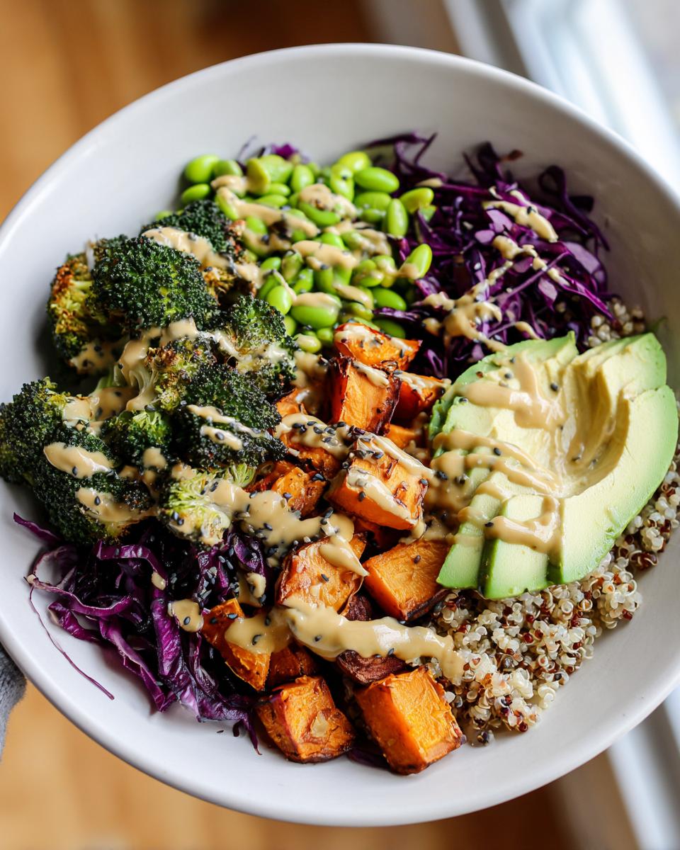 Close-up of a vibrant Vegan Buddha Bowl featuring roasted sweet potatoes, broccoli, avocado, and edamame with tahini dressing.
