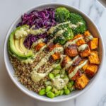 Overhead view of a vibrant Vegan Buddha Bowl featuring quinoa, roasted sweet potatoes, broccoli, and creamy dressing.