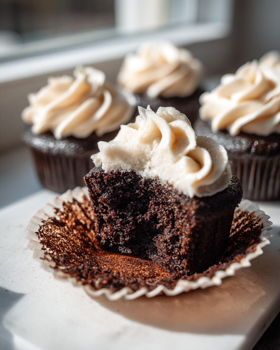 Close-up of a Black Velvet Cupcake cut in half showing moist dark cake and cream cheese frosting.