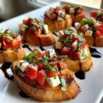 Several Caprese Crostini Ghosts topped with diced tomatoes, mozzarella, and basil, drizzled with balsamic glaze.