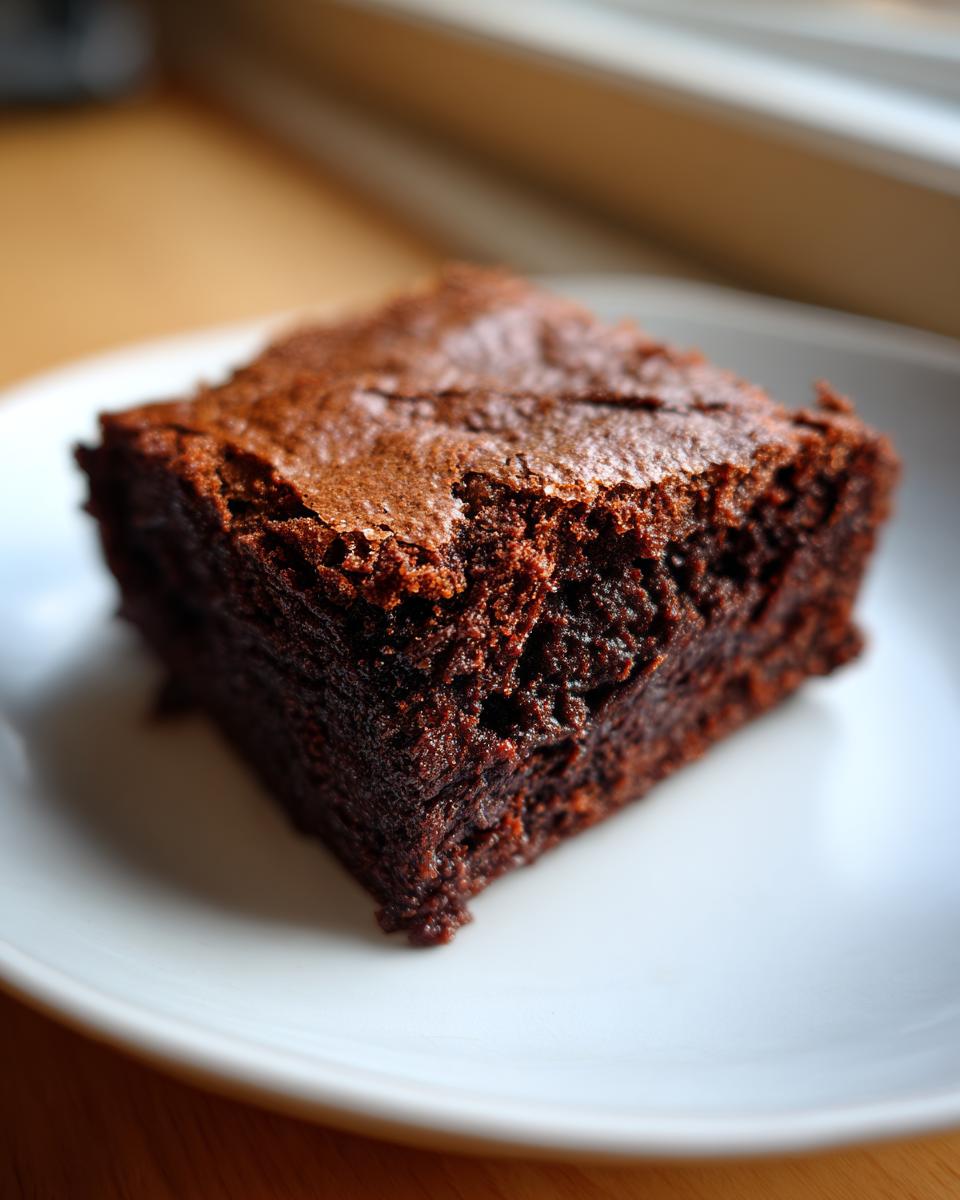 A single, rich, dark chocolate square of Chewbacca Brownies with a crackly top, served on a white plate.