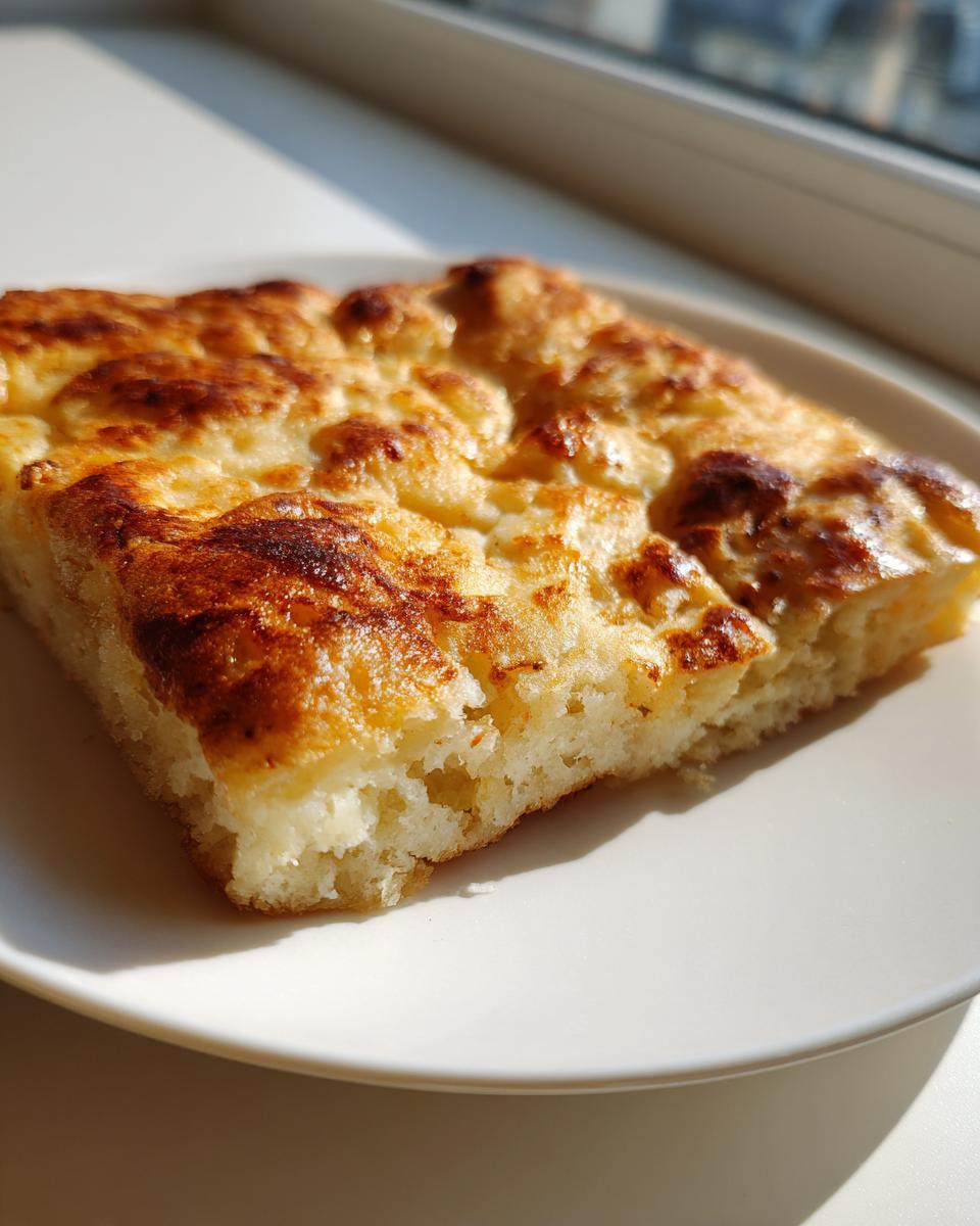 Close-up of a golden-brown, flaky square piece of Msemen Moroccan Pancake resting on a white plate.