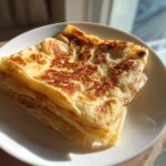 A stack of golden brown, flaky Msemen Moroccan Pancake layers served on a white plate.