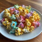 A close-up of vibrant, multi-colored Hocus Pocus Popcorn piled high on a white plate.