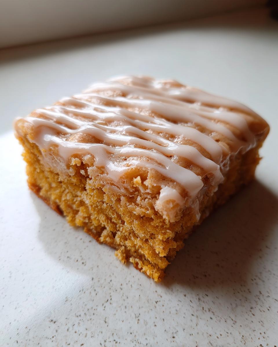 A single, moist square of Pumpkin Spice Latte Bars topped with a drizzle of white glaze.