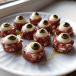 Close-up of ten Salami Mozzarella Eyeballs appetizers arranged on a white plate, ready for serving.