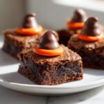 A close-up of fudgy Witch Hat Brownies decorated with a chocolate kiss and orange candy base.