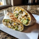 A close-up of Chicken Avocado Ranch Burritos cut in half, showing chunks of chicken, avocado, and cheese filling.