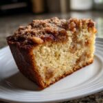 Close-up of a moist slice of Swedish Apple Cake featuring a golden crumb and a thick, sugary cinnamon crumble topping.